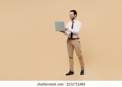 Full Body Fun Smiling Young Successful Employee Business Man Corporate Lawyer 20s Wear White Shirt Red Tie Glasses Work In Office Hold Use Laptop Pc Computer Isolated On Plain Beige Background Studio