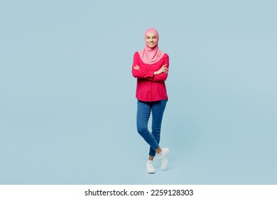 Full body fun young arabian asian muslim woman wear pink abaya hijab hold hands crossed folded isolated on plain pastel light blue cyan background studio portrait. People uae islam religious concept - Powered by Shutterstock