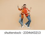 Full body fun young couple two friends family man woman wear casual clothes point index finger aside on area waving hand together isolated on pastel plain light beige color background studio portrait