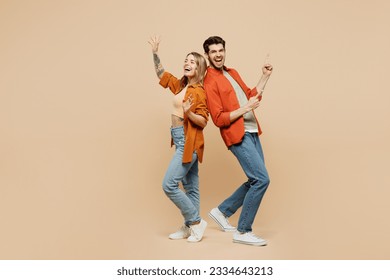 Full body fun young couple two friends family man woman wear casual clothes point index finger aside on area waving hand together isolated on pastel plain light beige color background studio portrait - Powered by Shutterstock