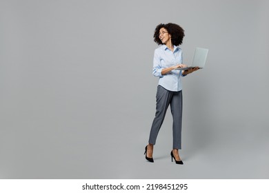 Full Body Fun Young Employee Business Corporate Lawyer Woman Of African American Ethnicity In Shirt At Office Hold Use Work On Laptop Pc Computer Look Aside On Workspace Isolated On Grey Background