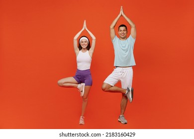 Full Body Fun Young Fitness Trainer Instructor Sporty Two Man Woman In Headband T-shirt Do Yoga Exercises Spend Weekend In Home Gym Isolated On Plain Orange Background Workout Sport Lifestyle Concept