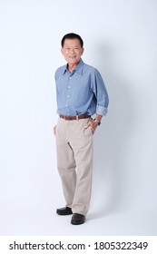 Full Body Of An Happy Asian Old Man In Blue Shirt And Beige Pants Standing In Studio White Background.