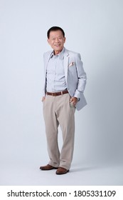 Full Body Of An Happy Asian Old Man In Light Blue Suit And Beige Pants Standing In Studio White Background.