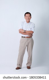 Full Body Of An Happy Asian Old Man In Light Grey Polo Shirt And Beige Pants Standing In Studio White Background.