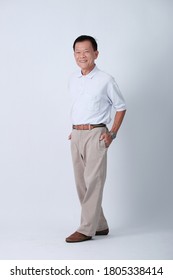 Full Body Of An Happy Asian Old Man In Light Grey Polo Shirt And Beige Pants Standing In Studio White Background.