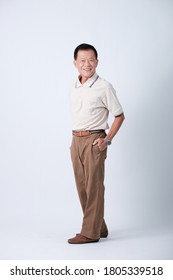 Full Body Of An Happy Asian Old Man In Beige Polo Shirt And Brown Pants Standing In Studio White Background.