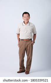 Full Body Of An Happy Asian Old Man In Beige Polo Shirt And Brown Pants Standing In Studio White Background.