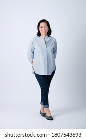 Full Body Of An Happy Asian Old Woman In Light Blue Shirt And Dark Blue Pants Standing In Studio White Background.