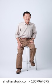 Full Body Of An Happy Asian Old Man Sitting In Studio White Background.