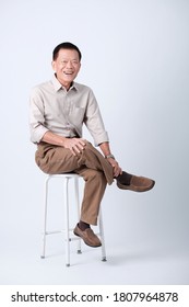 Full Body Of An Happy Asian Old Man Sitting In Studio White Background.