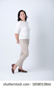 Full Body Of An Happy Asian Old Woman In White Shirt And Beige Pants Standing In Studio White Background.