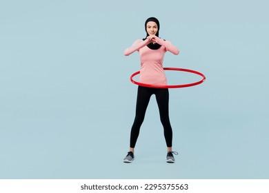 Full body happy fun young asian muslim fitness trainer sporty woman wear pink abaya hijab spend time in home gym using hula hoop isolated on plain blue background studio. Workout sport fit abs concept - Powered by Shutterstock