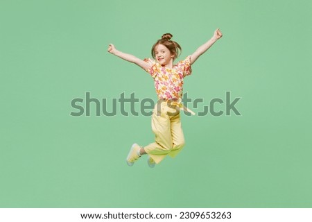 Full body happy little child kid girl 6-7 years old wear casual clothes jump high raise up hands isolated on plain pastel green background studio portrait. Mother's Day love family lifestyle concept