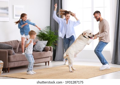 Full body of happy playful family: parents and little kids with cute purebred Labrador retriever dog having fun and dancing together in living room at home - Powered by Shutterstock