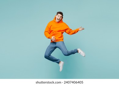 Full body happy singer young man he wears orange hoody casual clothes jump high play do air guitar gesture isolated on plain pastel light blue cyan color background studio portrait. Lifestyle concept - Powered by Shutterstock