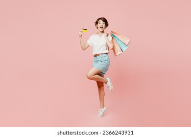 Full body happy surprised shocked young woman wear casual clothes hold shopping paper package bags credit bank card isolated on plain pink color background studio. Black Friday sale buy day concept