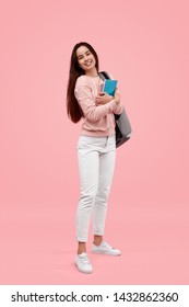 Full Body Happy Teen Student With Notebooks And Backpack Smiling And Looking At Camera While Standing Against Pink Background