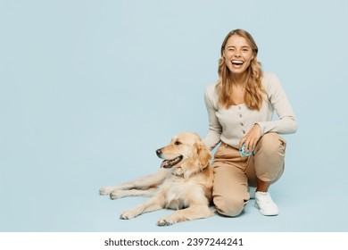 Full body happy young owner woman she wearing casual clothes kneeling hug cuddle embrace her best friend retriever dog wink isolated on plain light blue background studio. Take care about pet concept