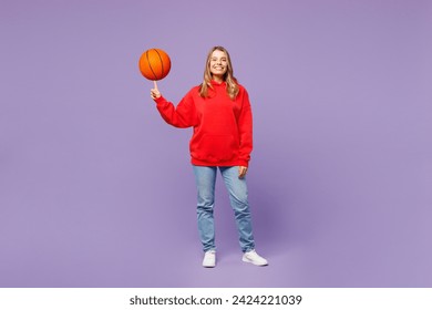 Full body happy young woman fan wear red hoody cheer up support basketball sport team hold in hand spin on finger ball looking camera isolated on plain purple background studio. Sport leisure concept - Powered by Shutterstock