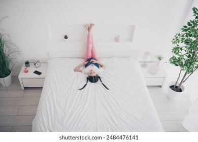 Full body high angle view portrait of adorable small girl sleep hold book wear pajama comfy bed bedroom apartment indoors
