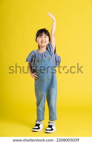 full body image of beautiful asian baby girl on yellow background