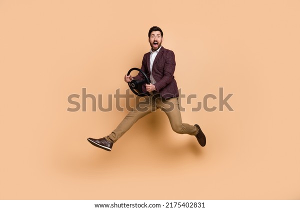 Full body image of successful businessman\
driving riding automobile hurry to conference meeting isolated on\
beige color background