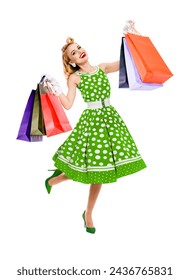 Full body jumping, running, dancing woman in pinup green color dress hold, showing carrying colorful shopping bags, isolated white background. Sales, rebates consumer bank credit ad advertise concept.