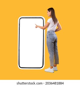 Full Body Length Back View Of Woman Using Big Smartphone With Blank White Screen And Touching Display Panel With Finger, Cheerful Lady Standing On Yellow Background, Ordering Food Delivery, Mock Up - Shutterstock ID 2036481884