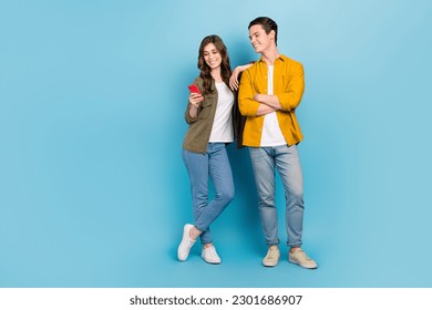 Full body length cadre of positive good mood couple choosing home decor website hold phone browsing ikea internet isolated on blue color background - Shutterstock ID 2301686907