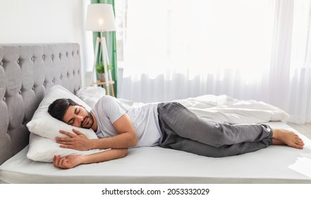 Full body length of calm arab man sleeping well on the side, resting, enjoying fresh cotton bedding, soft pillow and comfy mattress, banner, free space