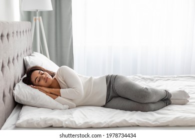 Full body length of calm young black woman sleeping well on the side. Beautiful African American lady resting, enjoying fresh cotton bedding, soft pillow and comfy mattress, banner, free copy space