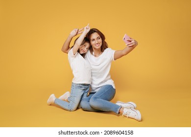 Full Body Length Happy Woman In Basic White T-shirt Sit On Floor Do Selfie Child Baby Girl 5-6 Years Old Mom Mum Little Kid Daughter Isolated On Yellow Color Background Studio Mother's Day Love Family