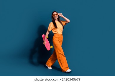 Full body length photo of sportive woman walking wearing touching sunglasses with her present skate isolated on dark blue color background - Powered by Shutterstock