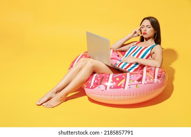 Full Body Length Sad Tired Young Woman Wear Red Blue Swimsuit Sit On Inflatable Ring Work On Pc Laptop Isolated On Vivid Yellow Color Wall Background Studio. Summer Hotel Pool Sea Rest Sun Tan Concept