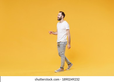 Full Body Length Side View Cheerful Young Bearded Man In White Casual T-shirt Walking Going Step Look Aside Isolated On Yellow Background Studio Portrait. People Lifestyle Concept. Mock Up Copy Space