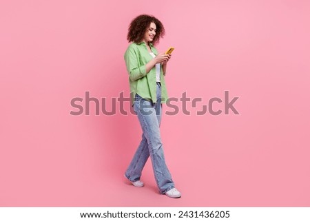 Full body length size photo of young woman strolling with smartphone using snapchat plus version isolated on pink color background