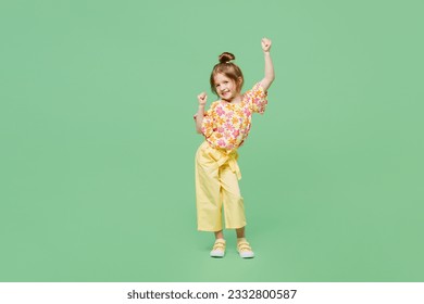 Full body little child kid girl 6-7 years old wears casual clothes doing winner gesture celebrate clench fists say yes isolated on plain green background. Mother's Day love family lifestyle concept - Powered by Shutterstock