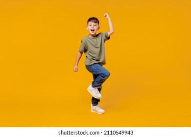 Full body little small fun happy boy 6  7 years old wearing green t  shirt do winner gesture clench fist isolated plain yellow background studio portrait  Mother's Day love family lifestyle concept