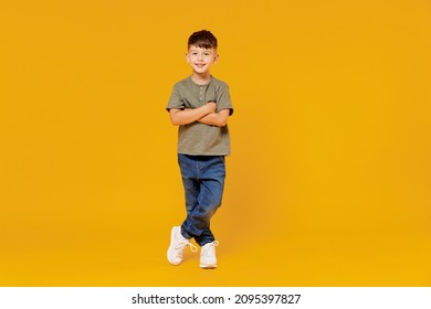 Full body little small smiling happy boy 6  7 years old wearing green t  shirt hod hands crossed folded look camera isolated plain yellow background studio Mother's Day love family lifestyle concept