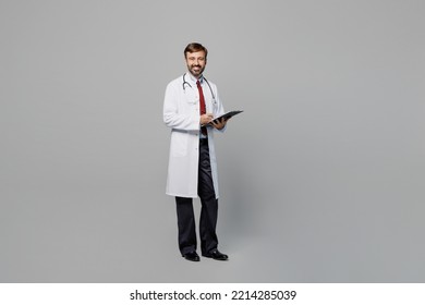 Full body male doctor happy cheerful man wears white medical gown suit work in hospital hold clipboard with paper documents isolated on plain grey color background studio. Healthcare medicine concept - Shutterstock ID 2214285039