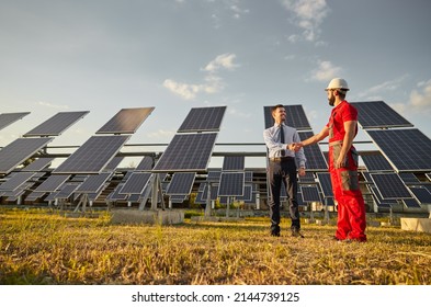 Full Body Of Male Entrepreneur In Formal Wear Making Agreement With Technician In Uniform And Hardhat In Field With Solar Panels