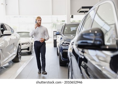 Full Body Man Happy Customer Male Buyer Client Wear White Shirt Talk By Mobile Cell Phone Choose Auto Want Buy New Car Automobile In Showroom Vehicle Dealership Store Motor Show Indoor. Sales Concept.