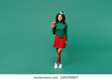 Full body merry little kid teen girl wears hat casual clothes posing hold takeaway delivery cup coffee to go isolated on plain green background. Happy New Year celebration Christmas holiday concept - Shutterstock ID 2396398847