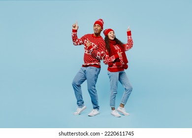 Full body merry smiling young couple two man woman wear red Christmas sweater Santa hat posing point finger up dance isolated on plain pastel light blue background. Happy New Year 2023 holiday concept - Powered by Shutterstock