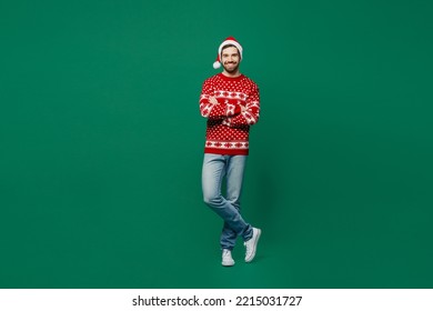 Full body merry young man wear red warm knitted sweater Santa hat posing hold hands crossed folded look camera isolated on plain dark green background studio. New Year 2023 holiday celebration concept - Powered by Shutterstock