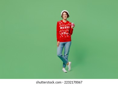 Full body merry young woman wear xmas sweater Santa hat posing hold takeaway delivery craft paper brown cup coffee to go isolated on plain pastel light green background. Happy New Year 2023 concept - Powered by Shutterstock