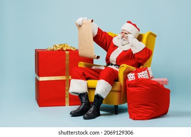 Full body old Santa Claus man 50s wear Christmas hat red suit sit in armchair near gifts bag read letter isolated on plain blue background studio. Happy New Year 2022 merry ho x-mas holiday concept - Powered by Shutterstock