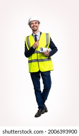 Full body of optimistic male construction engineer in formal suit and protective vest and hardhat with rolled blueprint pointing away, and smiling to camera against white background