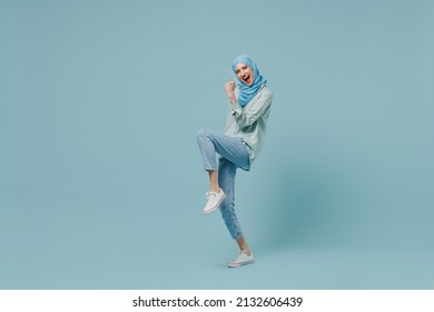 Full Body Overjoyed Young Arabian Asian Muslim Woman In Abaya Hijab Do Winner Gesture Clench Fist Isolated On Plain Blue Background Studio Portrait. People Uae Middle Eastern Islam Religious Concept